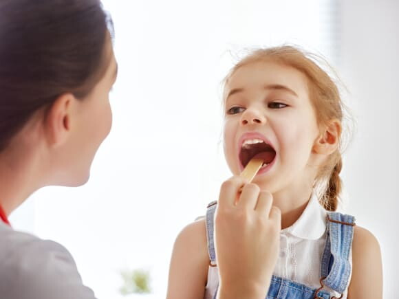uma médica examinando a boca de uma menina criança