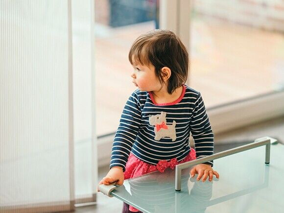 bebê em pé em uma mesa com protetor de quina 