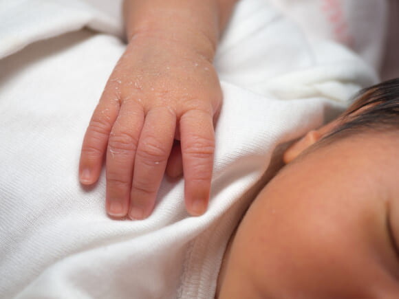 bebê recém nascido, com substância esbranquiçada em uma das mãos