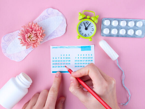 imagem com elementos que remetem a menstruação, como: absorvente interno e externo, cartela de remédios e um calendário
