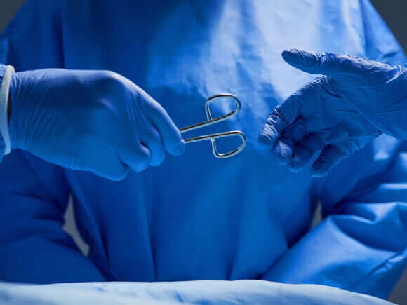 imagem de duas mãos com luvas cirúrgicas repassando um fórceps