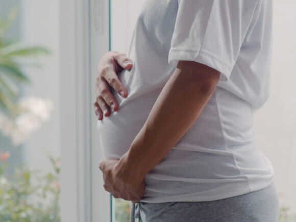 imagem de uma mulher grávida usando uma camiseta branco, com maior foco na barriga