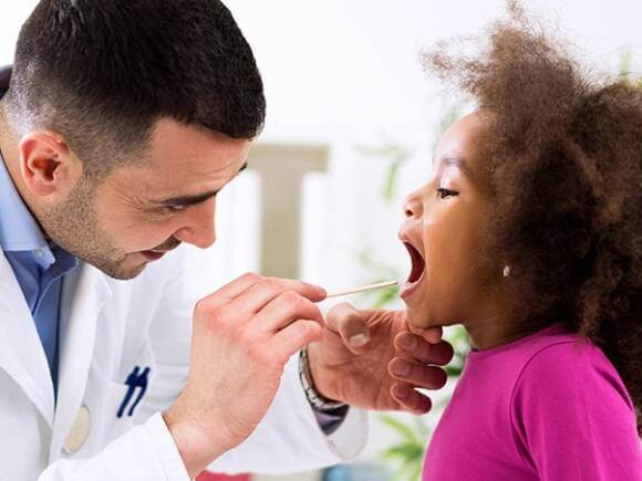 médico examinando a garganta de uma menina