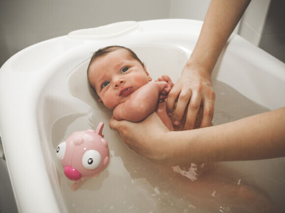 recém nascido tomando banho em banheira