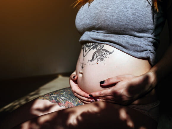 imagem de uma mulher grávida com tatuagem próxima a barriga
