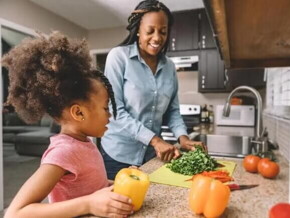 Mãe e filha na cozinha preparando refeição com alimentos ricos em ferro
