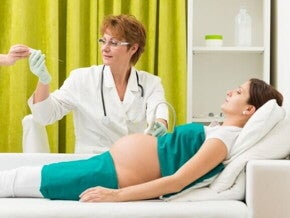 Médica realizando o procedimento de amniocentese em uma gestante deitada, utilizando uma agulha fina para coletar amostra do líquido amniótico.