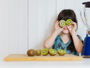 menina segurando duas rodelas de kiwi