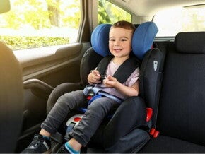 Um menino, sentado em um assento de elevação no carro, sorrindo e parecendo confortável.