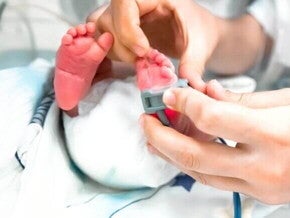 Pés de um bebê recém-nascido passando por uma avaliação pelas mão de um profissional da saúde. Pés de um bebê recém-nascido passando por uma avaliação pelas mão de um profissional da saúde.