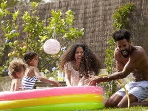 Foto de uma família se divertindo em um ambiente aberto com uma piscina de plástico colorida