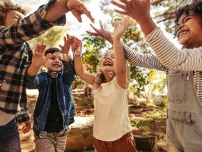 Crianças sorridentes num parque, brincando ao ar livre com bolhas de sabão