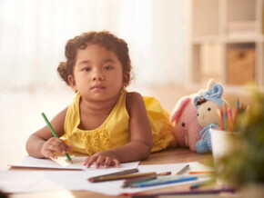 menina com blusa amarela segurando um lápis e desenhando em um caderno menina com blusa amarela segurando um lápis e desenhando em um caderno