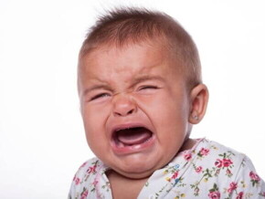Um bebê chorando, com a boca aberta, sobre um fundo branco Um bebê chorando, com a boca aberta, sobre um fundo branco