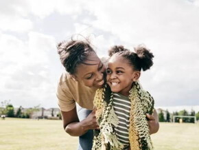 Mãe e filha rindo abraçadas em um campo de futebol Mãe e filha rindo abraçadas em um campo de futebol