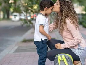 Uma mãe se agacha para se despedir do filho durante a rotina da guarda compartilhada.