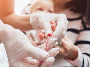 Mãe segurando bebê enquanto enfermeira colhe sangue para exame. Mãe segurando bebê enquanto enfermeira colhe sangue para exame.