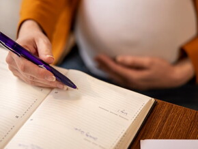 Imagem de um mulher grávida fazendo anotações em uma agenda Imagem de um mulher grávida fazendo anotações em uma agenda