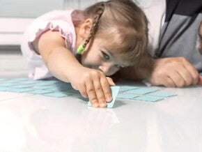 Uma menina e um adulto brincam de jogo de memória, um dos tipos de jogos educativos.