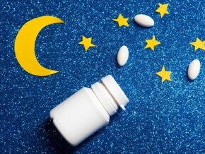 Frasco branco de comprimidos aberto com pílulas espalhadas sobre fundo azul com brilho, decorado com estrelas e uma lua amarela de papel. Frasco branco de comprimidos aberto com pílulas espalhadas sobre fundo azul com brilho, decorado com estrelas e uma lua amarela de papel.