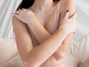 Mulher com top da cor da pele dela abraçando o corpo Mulher com top da cor da pele dela abraçando o corpo