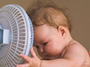 Um bebê com a cabeça próxima a um pequeno ventilador Um bebê com a cabeça próxima a um pequeno ventilador