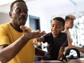ser pai Pai e filho cozinham juntos como uma homenagem de dia dos pais. O pai está mexendo uma panela e o filho, ao seu lado, o ajuda.