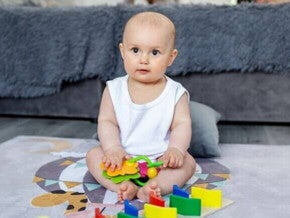 Um bebê sentado, com objetos lúdicos colocados à sua frente.