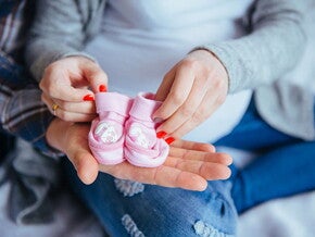 Tabela Chinesa da Gravidez: como funciona e para que serve mulher grávida segura um par de sapatinhos rosas de bebê