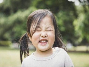 A foto destaca o rosto de uma menina fazendo caretas. A imagem remete ao tema de tique em crianças