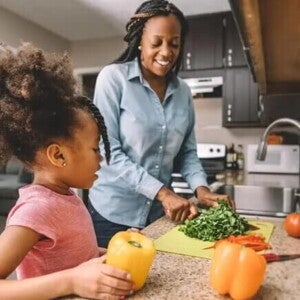 Mãe e filha na cozinha preparando refeição com alimentos ricos em ferro
