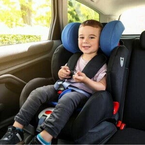 Um menino, sentado em um assento de elevação no carro, sorrindo e parecendo confortável.