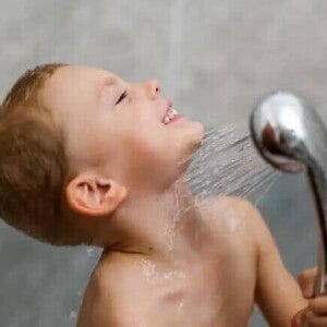 Autonomia infantil Um menino toma banho sozinho, exercitando sua autonomia infantil, com a ajuda de uma ducha móvel.