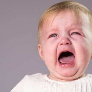Um bebê chorando com a boca aberta, sobre um fundo lilás. Um bebê chorando com a boca aberta, sobre um fundo lilás.