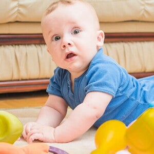 Bebê deitado de bruços no chão com alguns brinquedos em sua volta Bebê deitado de bruços no chão com alguns brinquedos em sua volta