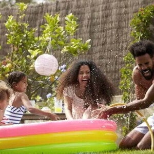 Foto de uma família se divertindo em um ambiente aberto com uma piscina de plástico colorida
