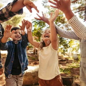 Crianças sorridentes num parque, brincando ao ar livre com bolhas de sabão Crianças sorridentes num parque, brincando ao ar livre com bolhas de sabão