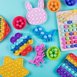 Diversos brinquedos sensoriais coloridos e de formas variadas, dispostos em uma superfície azul. Diversos brinquedos sensoriais coloridos e de formas variadas, dispostos em uma superfície azul.