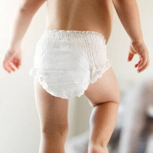 Bebê caminhando de fralda sob um fundo desfocado
