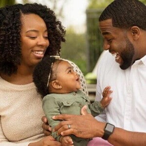 Mãe e pai sorrindo com o bebê no colo