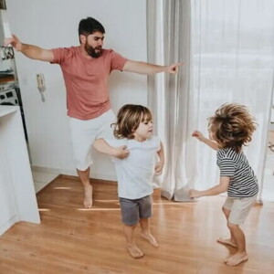 Pai e filhos pequenos brincam desenvolvendo a coordenação motora grossa dentro de casa. Pai e filhos pequenos brincam desenvolvendo a coordenação motora grossa dentro de casa.
