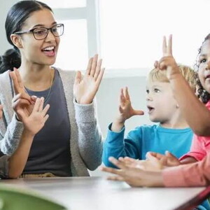 Imagem de uma tutora interagindo com crianças ao redor de uma mesa. Brincadeiras entre professores e crianças ajudam na adaptação na creche dos pequenos