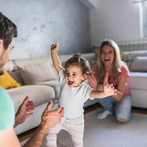 Pai e mãe em um momento feliz auxiliando nos primeiros passos da bebê. Pai e mãe em um momento feliz auxiliando nos primeiros passos da bebê.