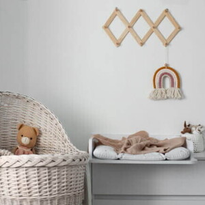 Quarto infantil com um berço ao lado de uma mesa em tons neutros.