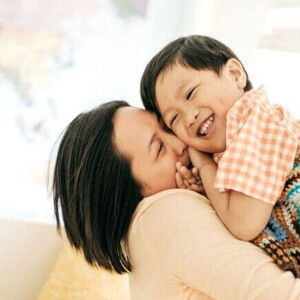 Uma mãe segurando o filho nos braços e sorrindo