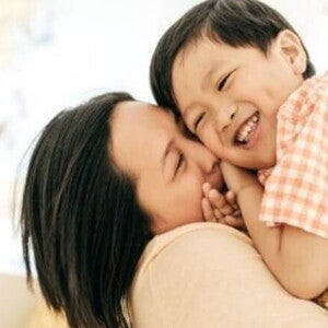 educacao positiva Uma mãe segurando o filho nos braços e sorrindo.