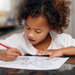 menina debruçada sobre mesa fazendo desenho menina debruçada sobre mesa fazendo desenho