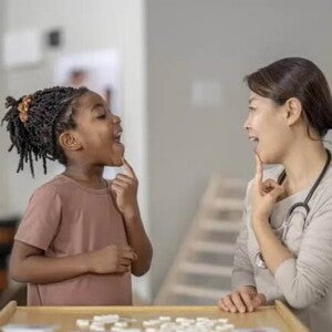 Gagueira infantil criança e mulher adulta fazem exercícios de voz em ambiente de escritório médico