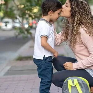 Uma mãe se agacha para se despedir do filho durante a rotina da guarda compartilhada.