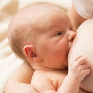 Um bebê recém-nascido sendo amamentado.